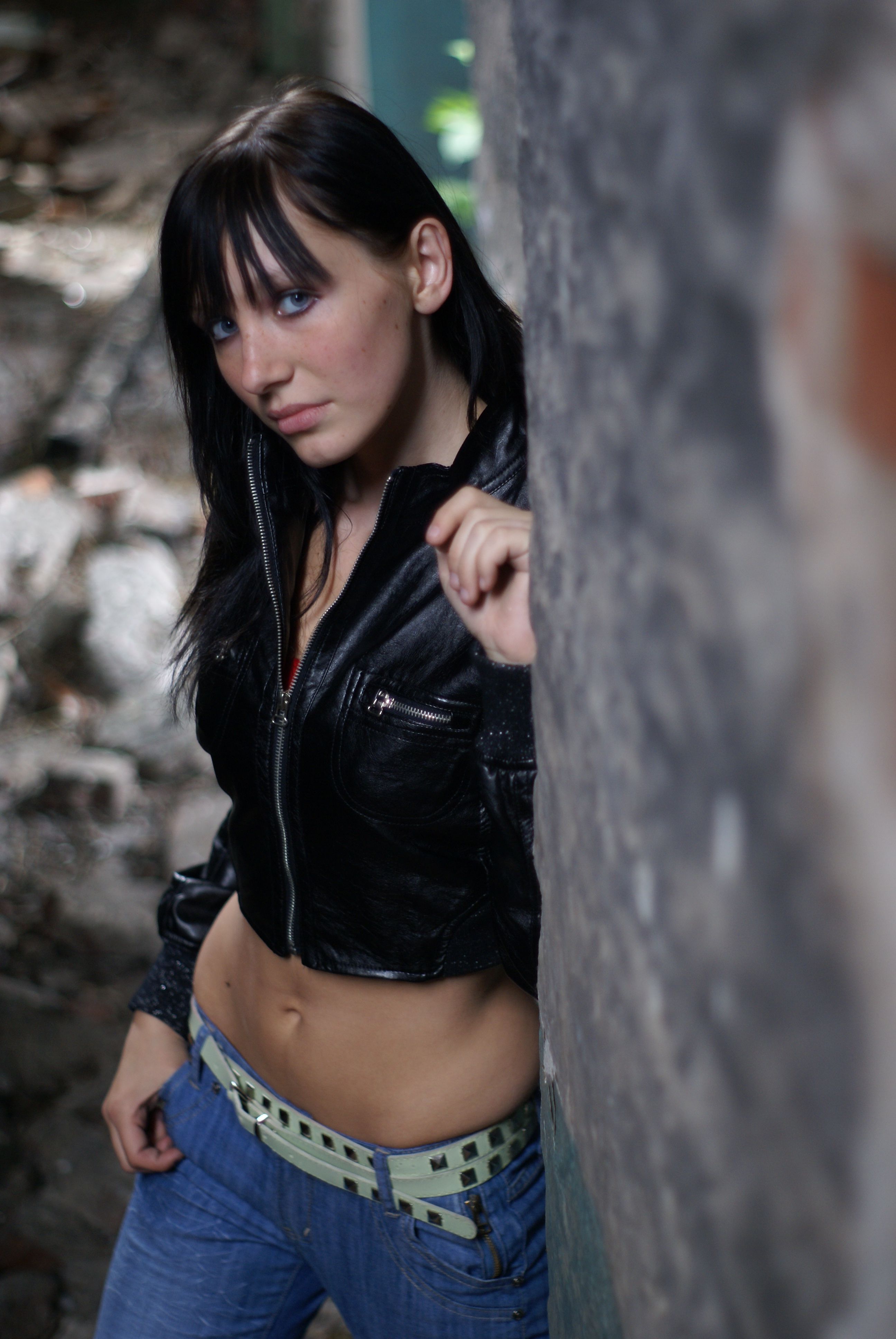 A woman in jeans and a black jacket leaning against a wall · Free Stock ...