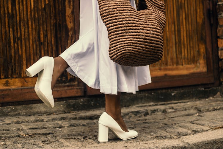 Woman Wearing White Dress And White High-heeled Shoes While Walking On Sidewalk