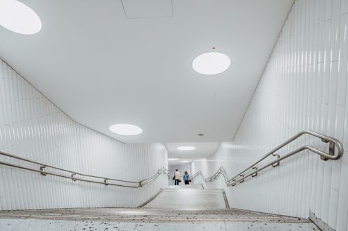Free Brightly lit underground staircase with sleek railings and two people ascending. Stock Photo