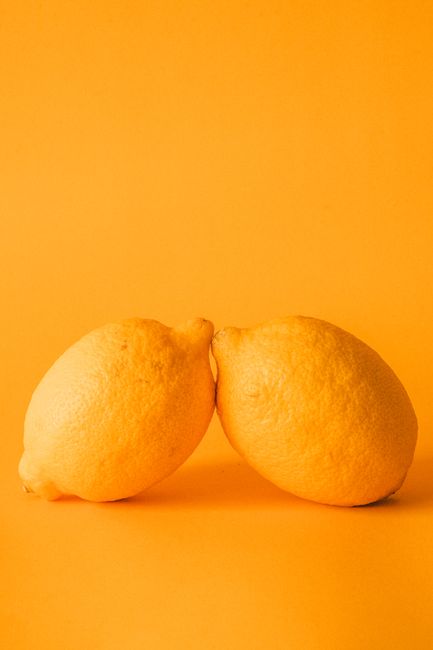 A striking image of two ripe lemons against a bright orange backdrop, emphasizing freshness.