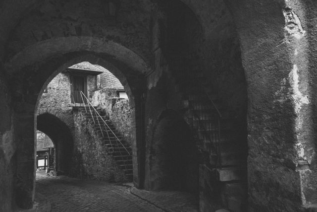 A dim stone archway inside an old vaulted hall, photo by Masood Aslami on Pexels