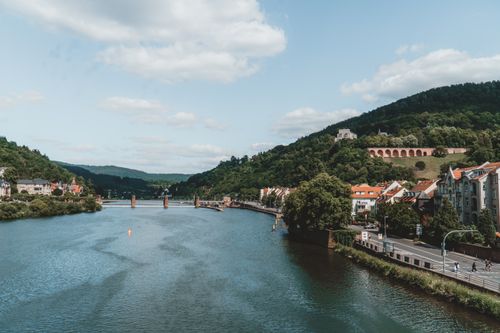 Free Picturesque scene of Heidelberg's Neckar River and historic bridge, surrounded by lush hills. Stock Photo
