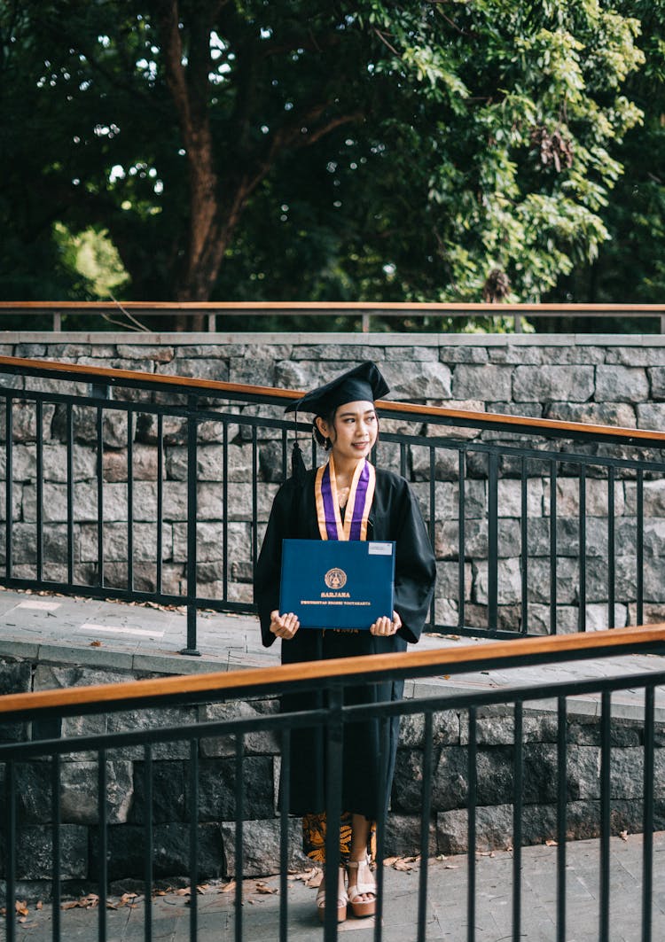 Dreamy Asian Female Bachelor With Diploma On Bridge