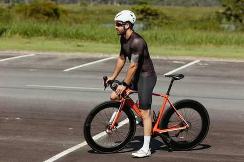 Free Cyclist in sports gear with a helmet riding a bike in a sunny parking area. Stock Photo