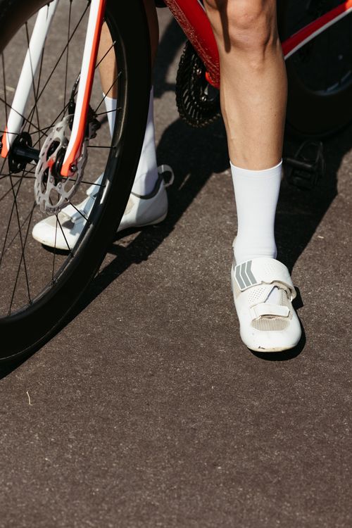 Free Cyclist wearing white shoes and socks, pedaling on an asphalt road with a bicycle. Stock Photo