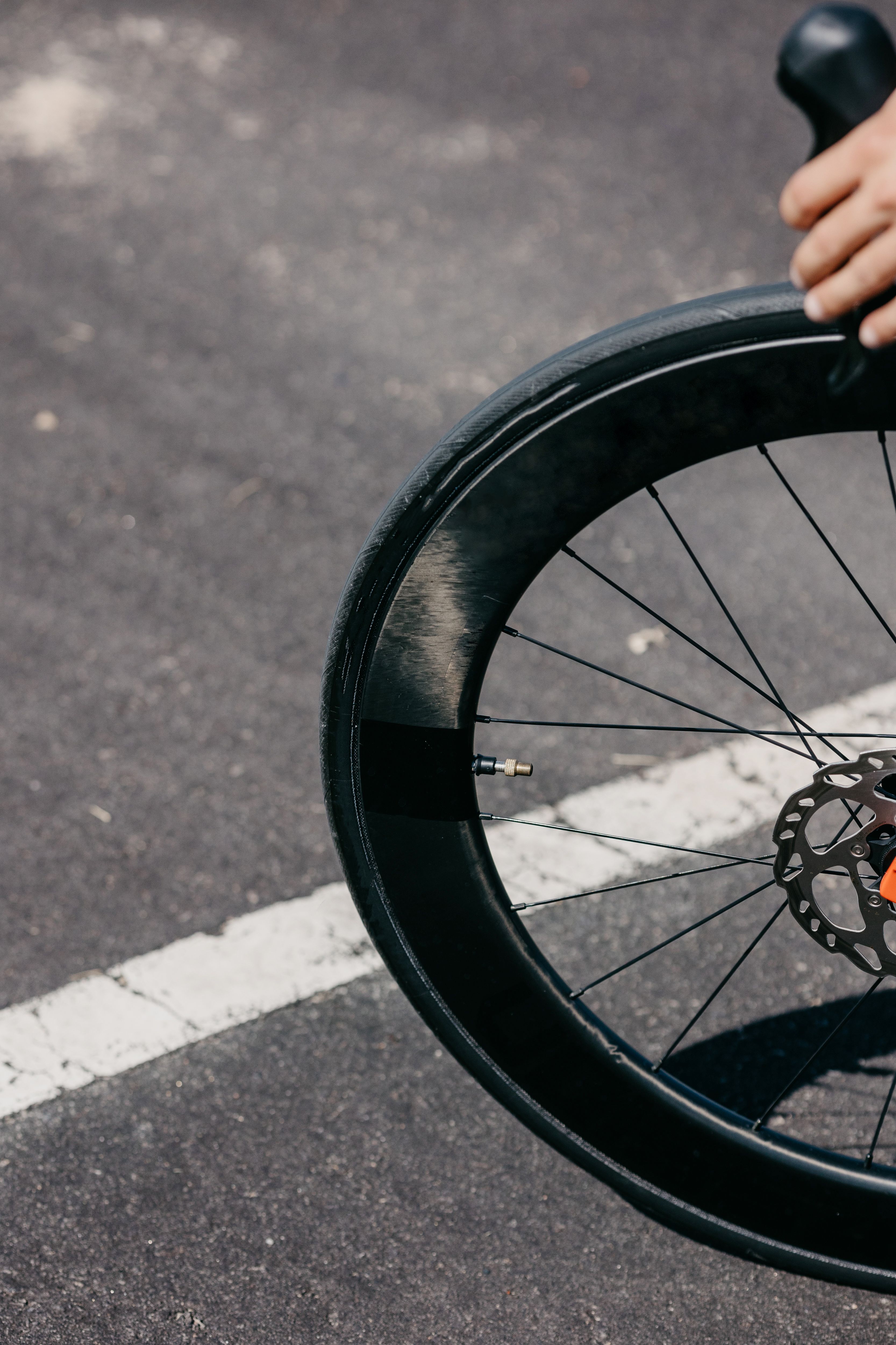A person holding a bicycle wheel with a black rim · Free Stock Photo