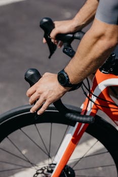 Close-up of cyclist's hands holding the handlebars of a racing bike on a sunny day.