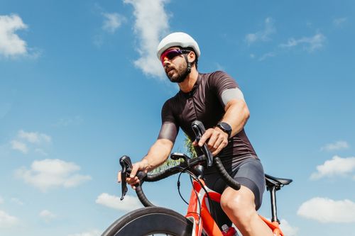 Free Athletic man cycling under a clear blue sky, showcasing fitness and leisure. Stock Photo