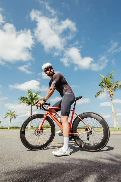 Free Man on a bicycle enjoying a sunny day with palm trees around. Stock Photo