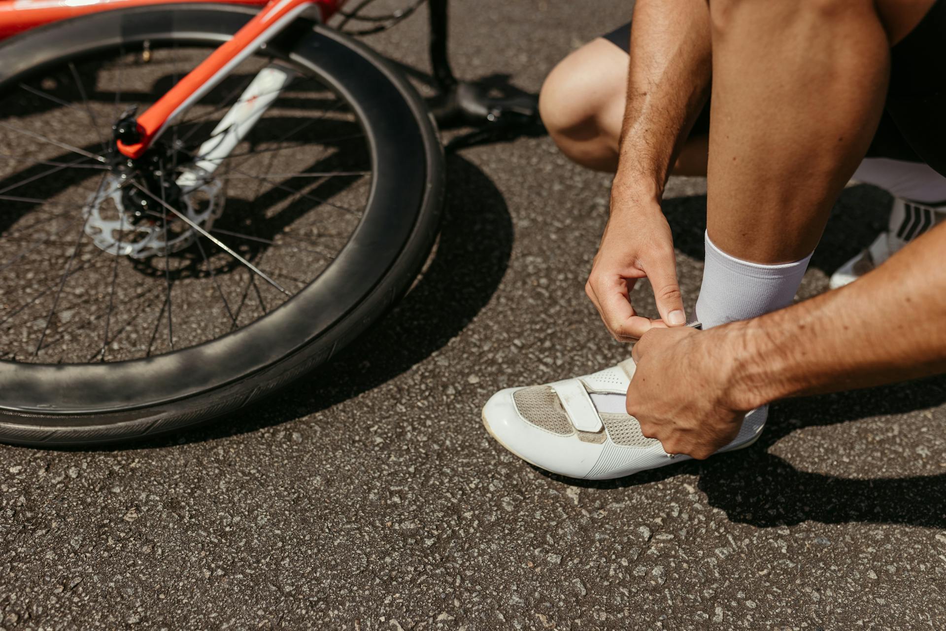 A cyclist laces up shoes next to a bike, ready for an outdoor journey.