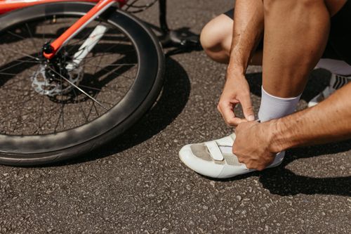 Free A cyclist laces up shoes next to a bike, ready for an outdoor journey. Stock Photo