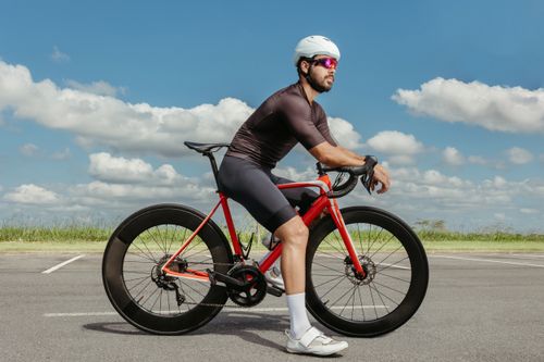 Free A cyclist in professional gear rides a modern bicycle on an open road under a clear sky. Stock Photo