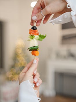 Healthy vegetable skewer with cheese and olives held by hand, perfect for holiday snacks.