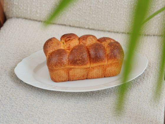 Shiny golden brioche loaf with rounded pull-apart sections resting on a white oval plate