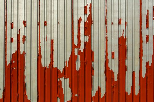 Free Close-up of a corrugated metal wall with red paint peeling off, showcasing aging and deterioration. Stock Photo
