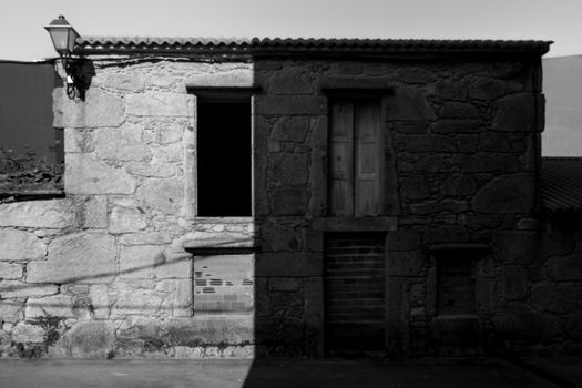 Black and white photo of an abandoned stone building facade with deep shadows.