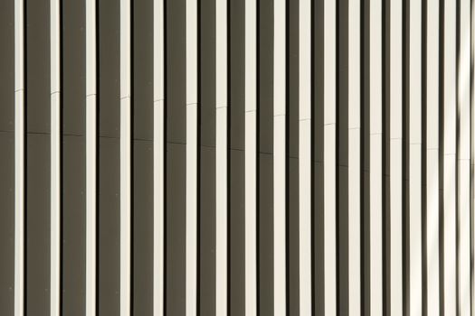 Close-up view of a modern building facade showcasing abstract vertical patterns in neutral tones.