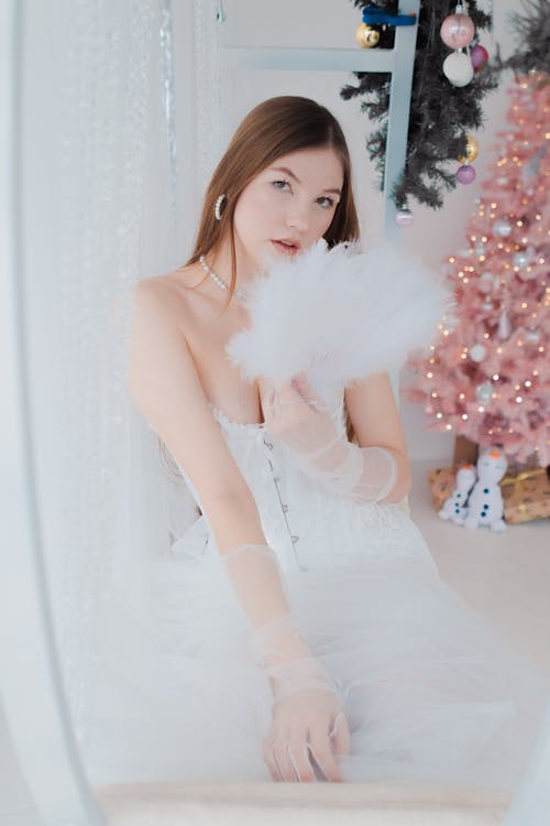 Young Woman Posing in a White Dress on the Background of Christmas Decorations