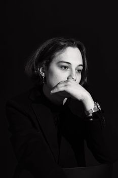 Introspective black and white portrait of a woman with hand over mouth wearing a wristwatch.
