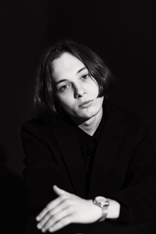 Free Black and white portrait of a young adult in a blazer, featuring a moody and elegant style. Stock Photo
