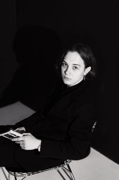 Elegant black and white portrait of a woman seated, exuding confidence and style.