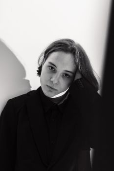 Black and white portrait of a young adult with a hand in hair, exuding a contemplative mood.