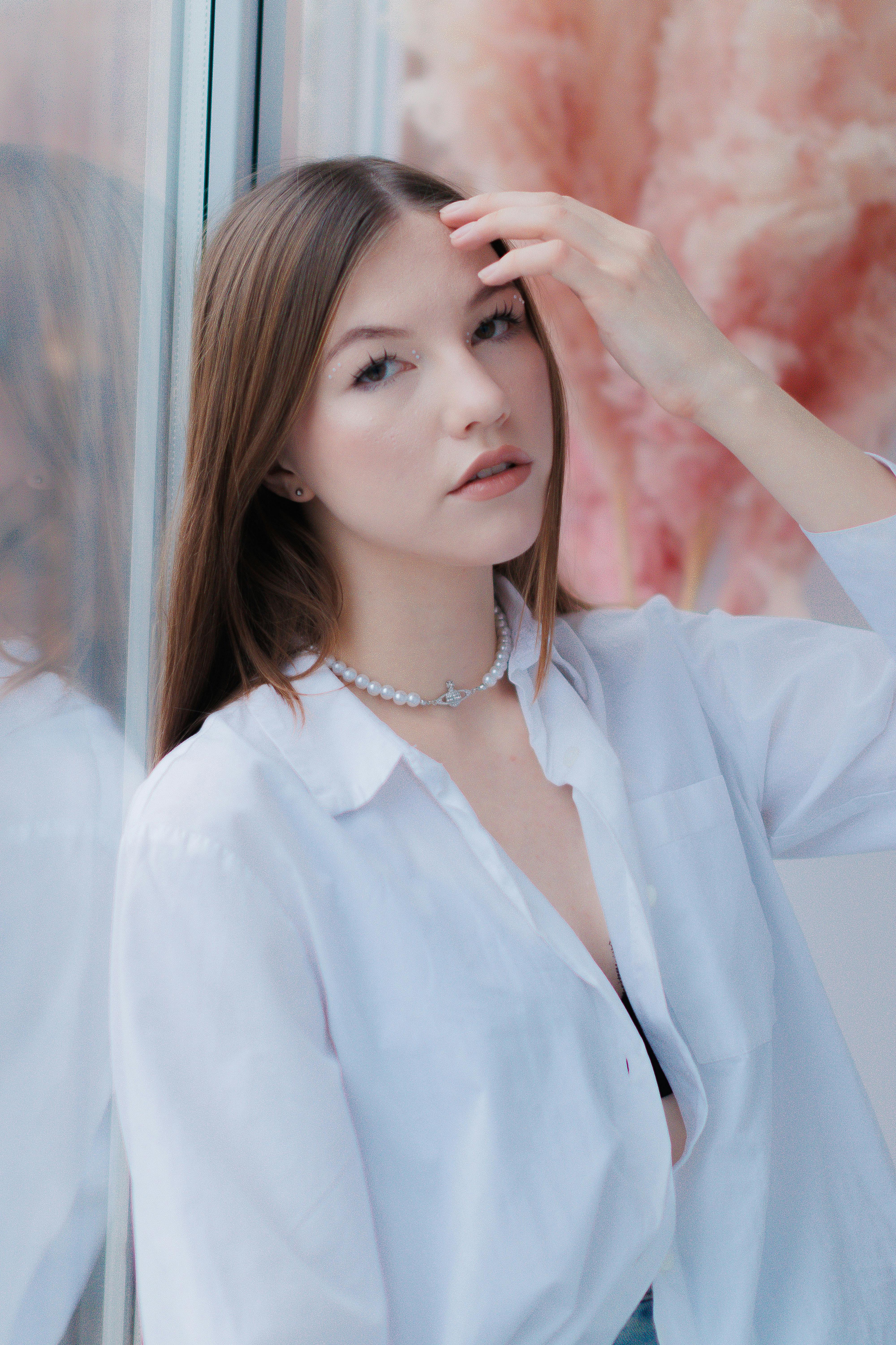 Stylish woman in a white shirt poses gracefully indoors.
