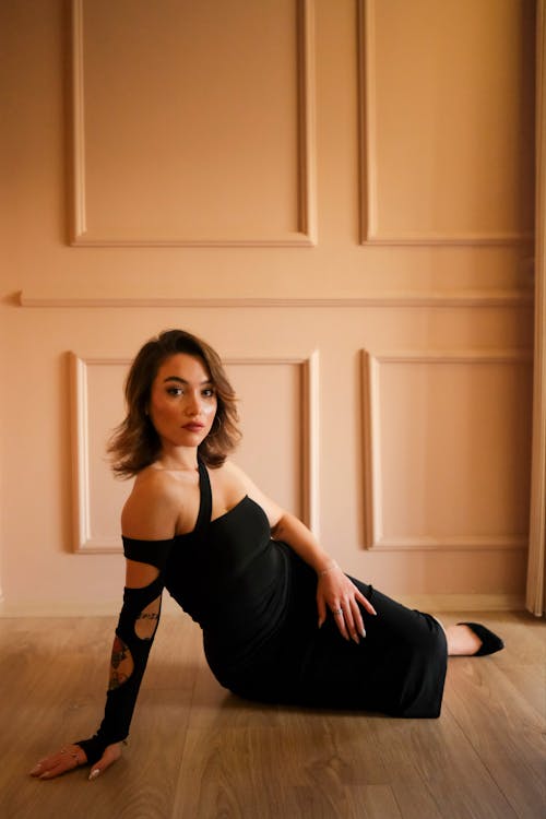 Woman in Black Dress Sitting on Floor and Posing