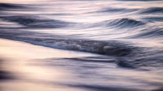 Gentle waves and a tranquil seascape captured at dusk, offering a moody and calming scene.