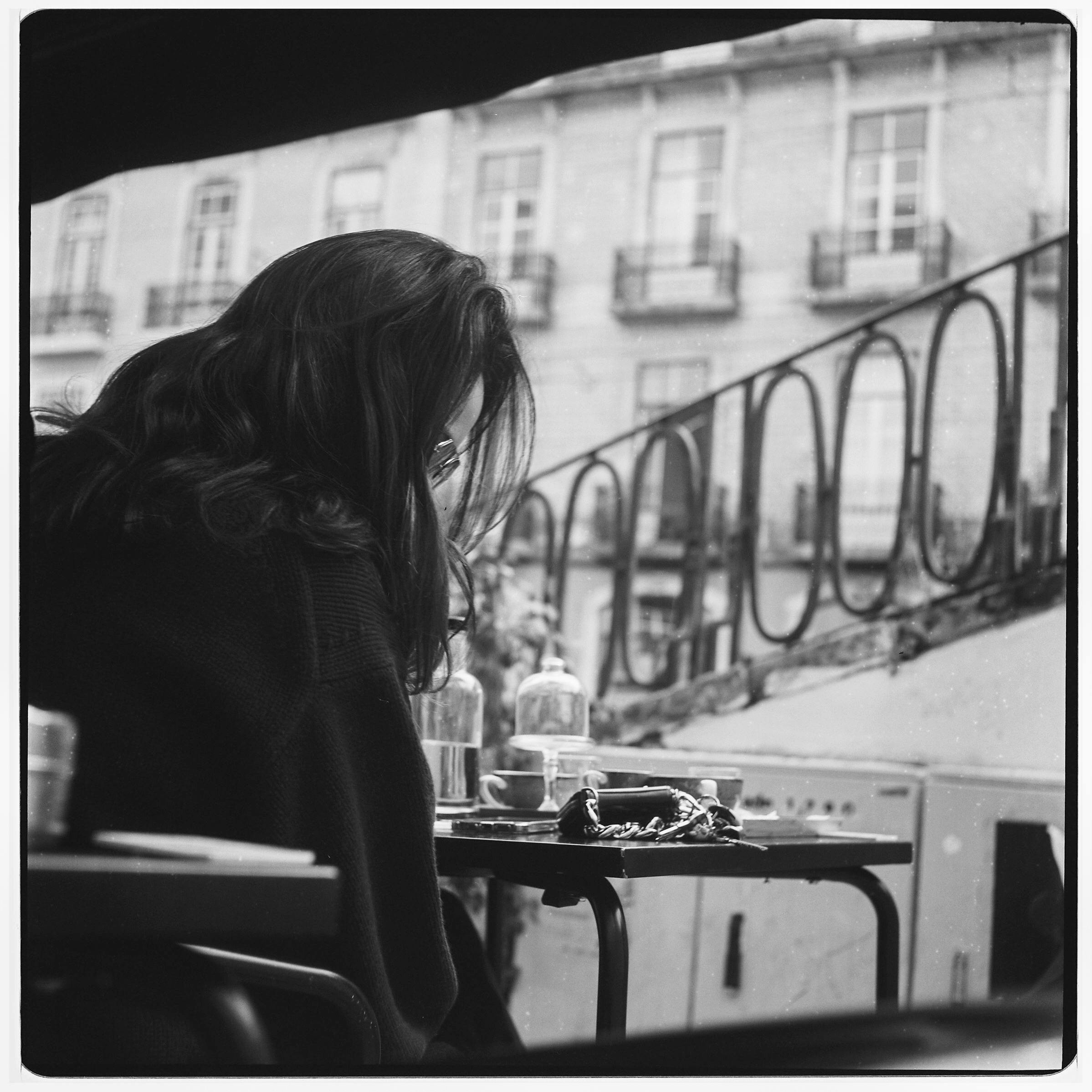 Captivating black and white photograph of a woman sitting in a Lisbon café.