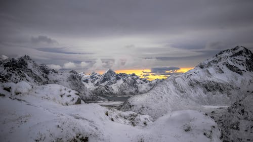 Scenic View of Rocky, Snowcapped Mountains under a Cloudy Sky 