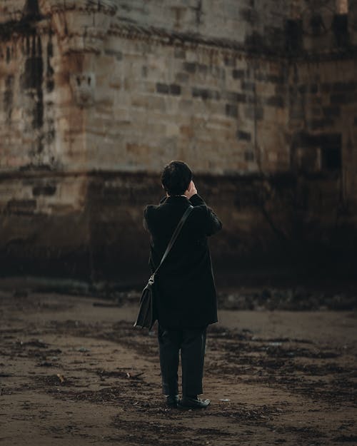 Back View of a Person Standing near an Old Building 