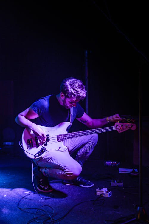 Free Man Tuning His Bass Guitar on Stage Stock Photo