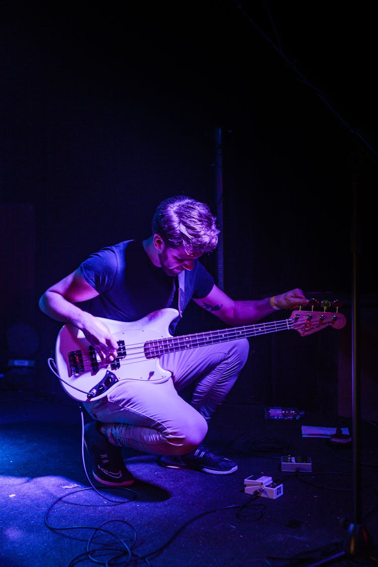 Man Tuning His Bass Guitar On Stage