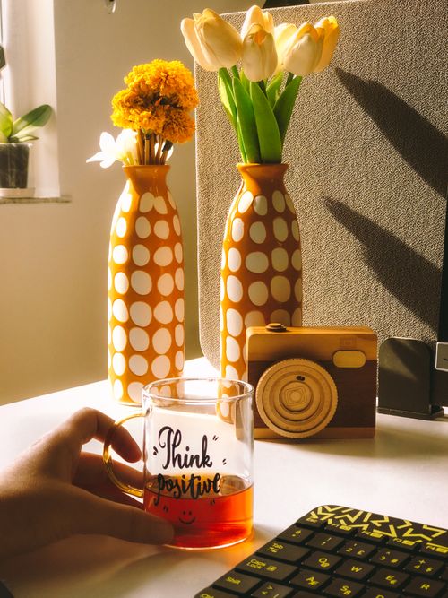 Free A cozy workspace with flowers, a decorative camera, and motivational mug for positive vibes. Stock Photo