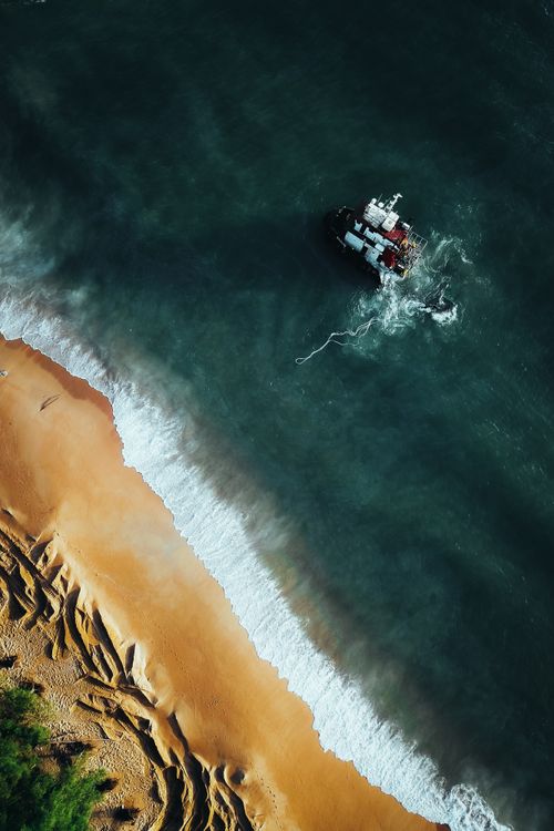 Free Drone shot of a fishing boat navigating Chukai coast in Terengganu, Malaysia. Stock Photo