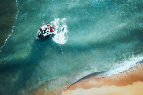 Free Aerial view of a shipwrecked boat on Chukai's sandy shore in Malaysia, surrounded by turquoise waters. Stock Photo