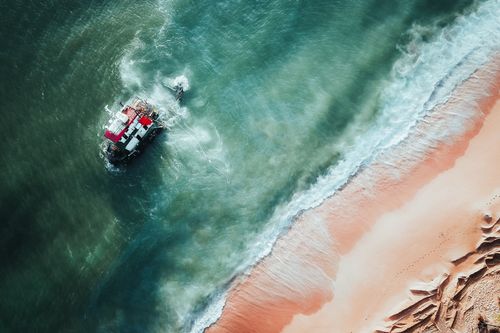 Free Aerial photo of a shipwreck near the sandy shores of Chukai, Malaysia, showcasing ocean waves. Stock Photo