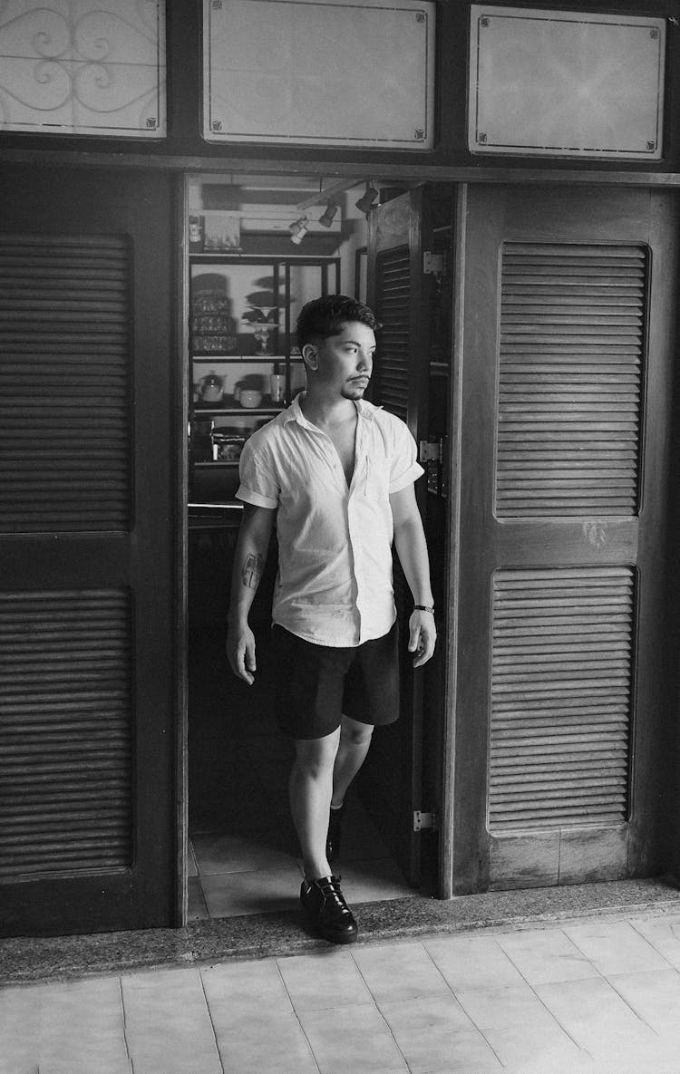 Black And White Photo Of A Man Walking Out The Door 