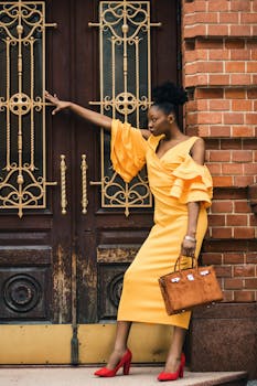 一位优雅的黑衣女子身着黄色连衣裙和红色高跟鞋，在装饰门旁摆着姿势