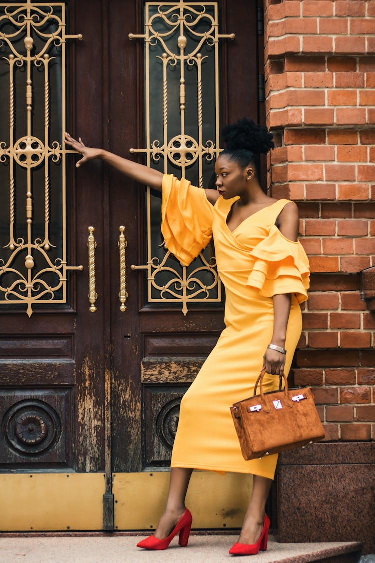 Woman Leaning On Brick Wall While Holding Handbag