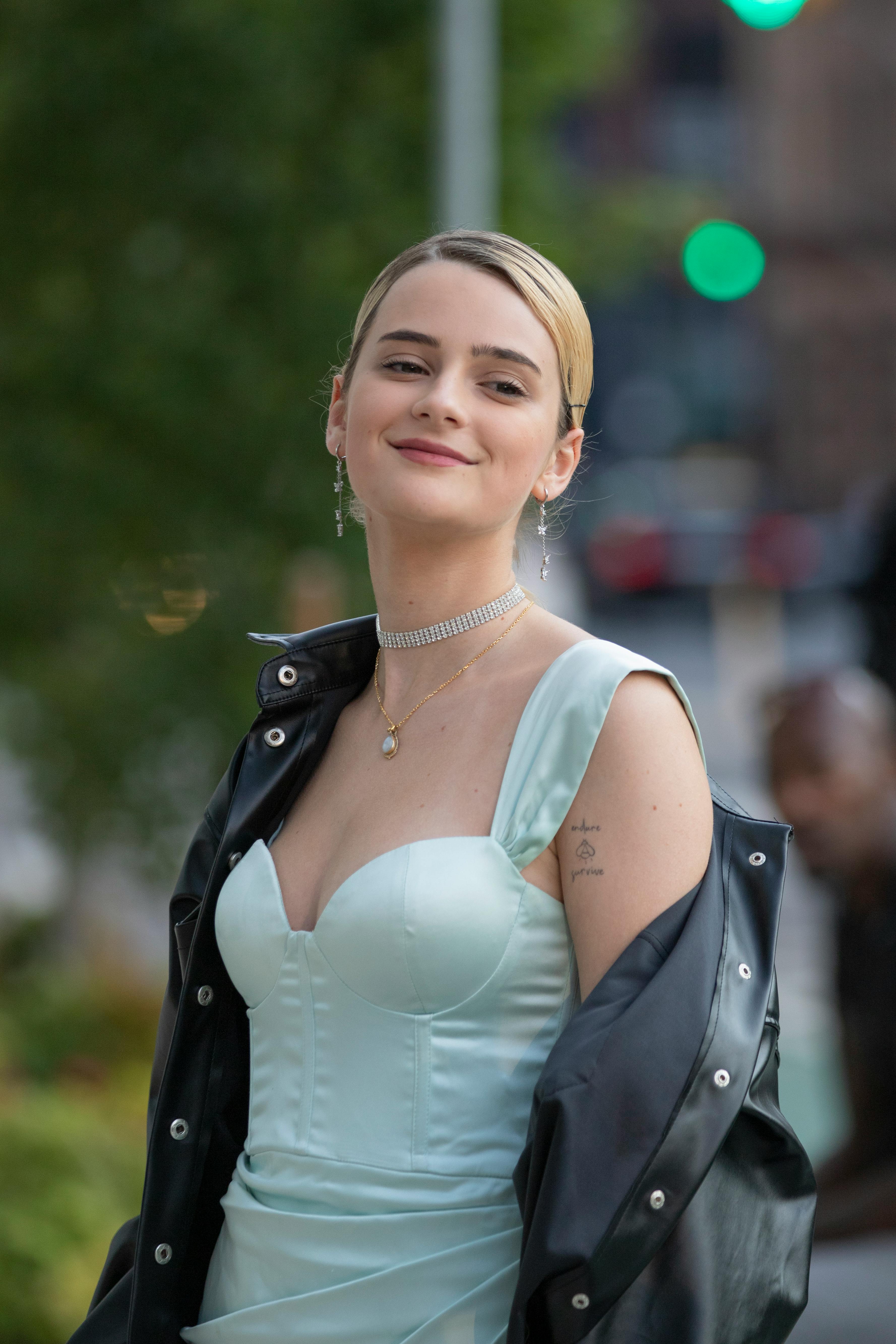 A woman in a strapless dress and leather jacket exuding urban sophistication outdoors.