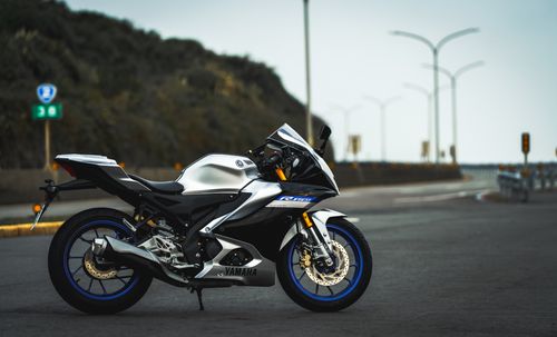 Free A sleek silver Yamaha R15 M motorcycle parked on an empty road, ideal for wallpaper. Stock Photo