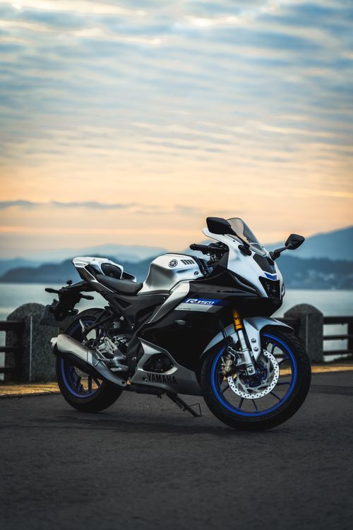 Free A sleek sport motorcycle parked on a seaside road with a stunning sunset backdrop. Stock Photo