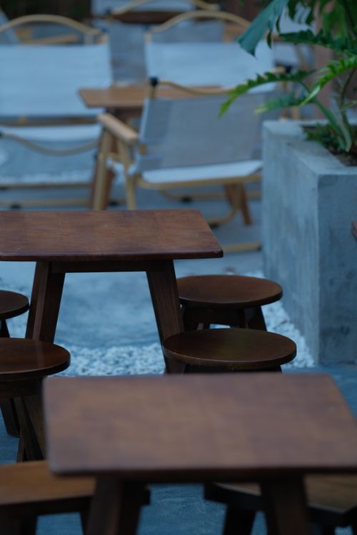 Free Charming outdoor patio featuring wooden tables and chairs, ideal for relaxation. Stock Photo