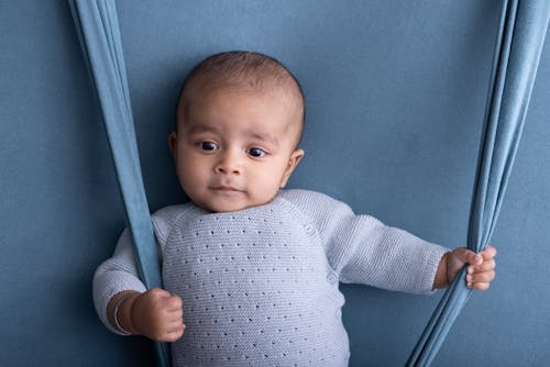 A baby is sitting on a blue background with a blue blanket