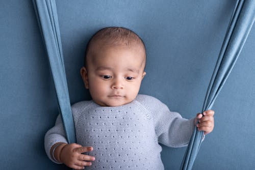 A baby is sitting on a blue blanket with a blue background