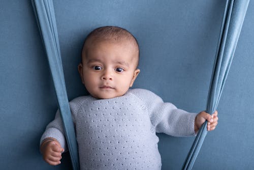 A baby is sitting on a blue background with a blue background