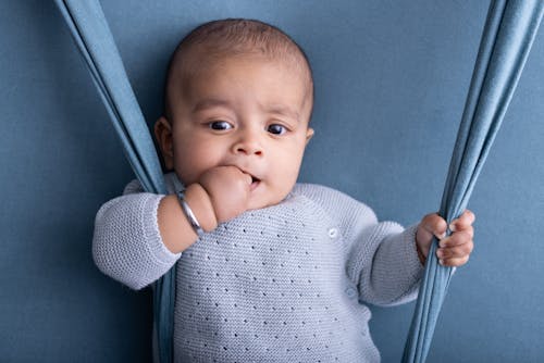 A baby is sitting on a swing with a blue blanket