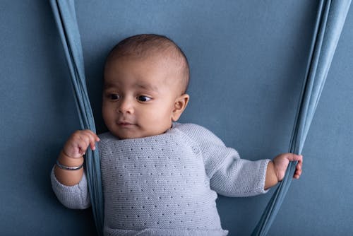 A baby is sitting on a blue background with a blue backdrop